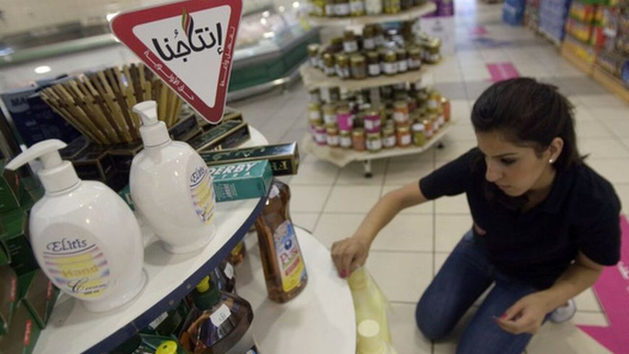 To match feature PALESTINIANS-ISRAEL/BOYCOTT A Palestinian worker sticks Intajuna ("Our Products") stickers on Palestinian goods displayed in a supermarket in the West Bank city of Ramallah August 2, 2009. Intajuna is one of many campaigns asking Palestinians to avoid Israeli products. After 40 years of occupation, the Palestinian economy is tied to Israel's, so attempts to reduce its dependence clash with hard realities. Picture taken August 2, 2009. To match feature PALESTINIANS-ISRAEL/BOYCOTT REUTERS/Fadi Arouri (WEST BANK POLITICS BUSINESS)