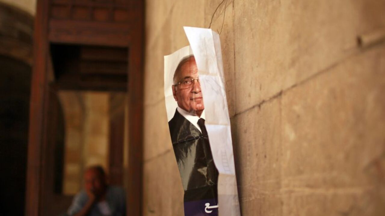 Man sits outside a shop as a poster of presidential candidate Shafiq is seen hanging on a wall in Cairo A man sits outside a shop as a poster of presidential candidate Ahmed Shafiq is seen hanging on a wall in Cairo June 13, 2012. The Brotherhood's Mohamed Mursi will face Shafiq, the last prime minister of ousted leader Hosni Mubarak, in a presidential run-off on June 16 and 17, the climax of Egypt's first free leadership contest after 16 months of military rule. REUTERS/Suhaib Salem (EGYPT - Tags: POLITICS CIVIL UNREST)