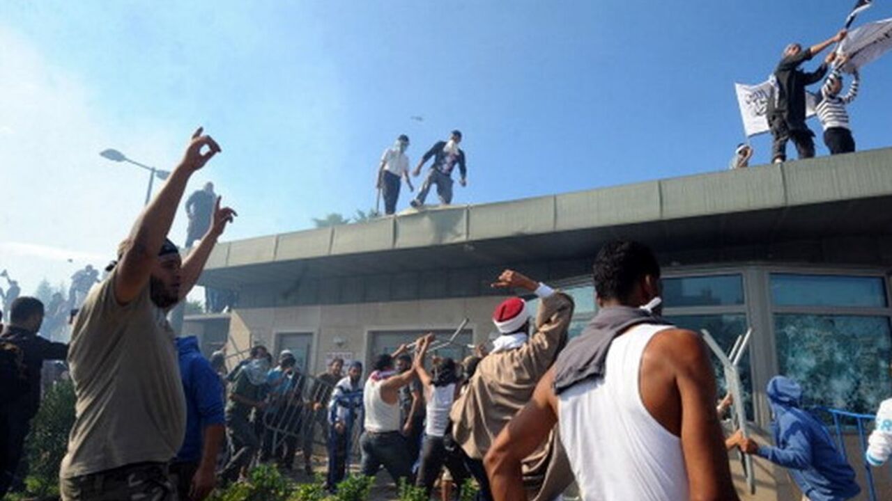 TUNISIA-US-ISLAM-UNREST-FILM-DEMO Tunisian protesters break into the US embassy in Tunis during a protest against a film mocking Islam on September 14, 2012. The demonstrators, acting aggressively, managed to clamber over one of the walls round the mission, near the car park where several vehicles had been set ablaze, the photographer said. AFP PHOTO/FETHI BELAID (Photo credit should read FETHI BELAID/AFP/GettyImages)
