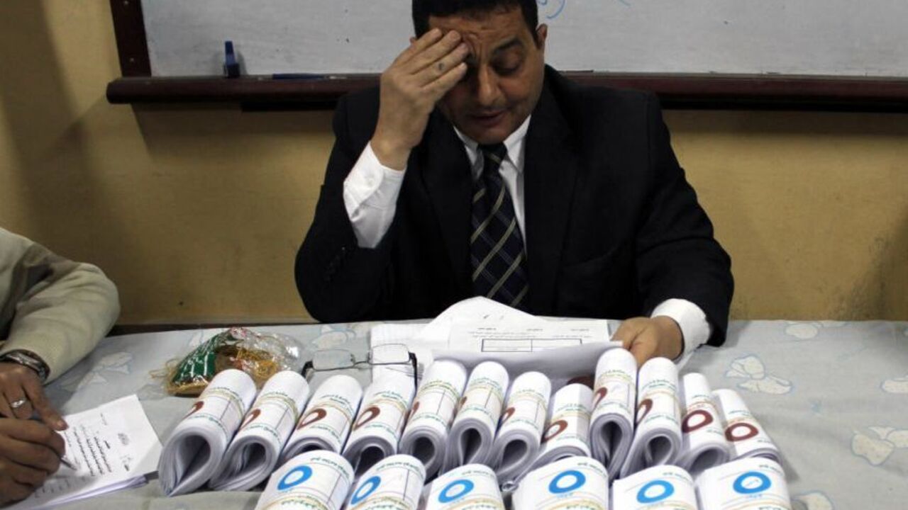 Supervising judge of El-Baheyya El-Burhaneyya polling station in Cairo's poor district of Sayyeda Zeinab fills the count forms after more than two hours of counting votes. Sunday Dec. 16, 2012.