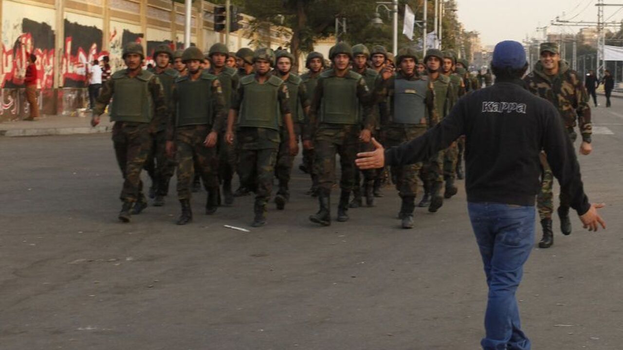 An anti-Mursi protester gestures to soldiers marching outside the Egyptian presidential palace in Cairo An anti-Mursi protester gestures to soldiers marching outside the Egyptian presidential palace in Cairo December 9, 2012. A concession offered by President Mohamed Mursi failed to placate opponents who accused him on Sunday of plunging Egypt deeper into crisis by refusing to postpone a vote on a constitution shaped by Islamists. REUTERS/Asmaa Waguih (EGYPT - Tags: POLITICS CIVIL UNREST MILITARY)