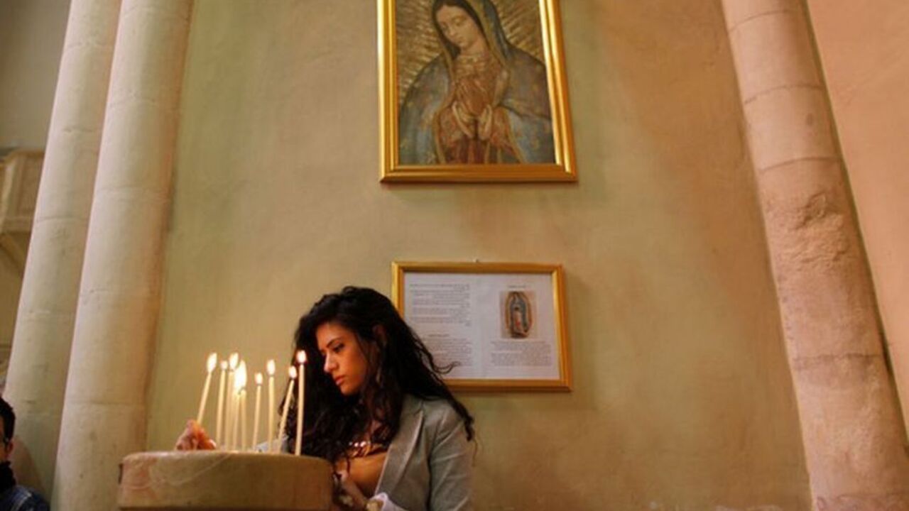 A Palestinian Christian lights a candle during a prayer to show solidarity with Gaza, at a Catholic church in the West Bank town of Beit Jala near Bethlehem A Palestinian Christian lights a candle during a prayer to show solidarity with Gaza, at a Catholic church in the West Bank town of Beit Jala near Bethlehem November 18, 2012. Israel bombed Palestinian militant targets in the Gaza Strip from air and sea for a fifth straight day on Sunday, preparing for a possible ground invasion while also spelling out its conditions for a truce. REUTERS/Ammar Awad (WEST BANK - Tags: POLITICS CIVIL UNREST RELIGION)