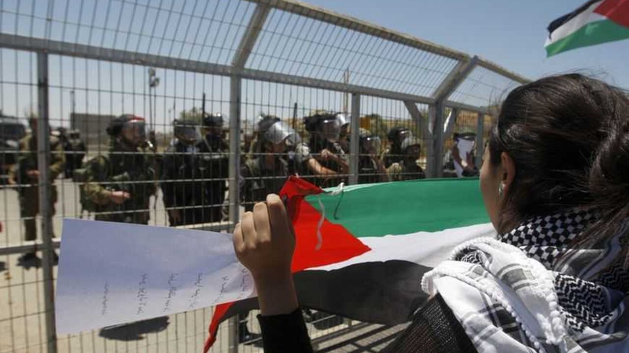 Palestinian protester holds a flag in front of Israeli security forces during a protest near Ramallah A Palestinian protester holds a flag in front of Israeli soldiers and border police during a protest outside Ofer prison near the West Bank city of Ramallah, marking the anniversary of the 1967 Middle East War, June 5, 2012. REUTERS/Mohamad Torokman (WEST BANK - Tags: POLITICS CIVIL UNREST)