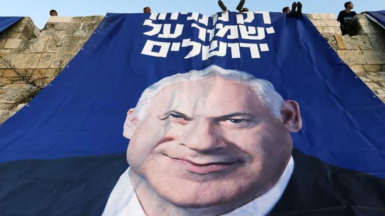 Likud-Yisrael Beitenu activists sit atop a wall surrounding Jerusalem's Old City after they hung a campaign banner depicting Israel's Prime Minister Netanyahu Likud-Yisrael Beitenu activists sit atop a wall surrounding Jerusalem's Old City after they hung a campaign banner depicting Israel's Prime Minister Benjamin Netanyahu January 20, 2013. Netanyahu said on Saturday a country with as many enemies as Israel cannot afford a weak ruling party, after polls ahead of Tuesday's parliamentary election showed a slide in his support. The banner reads "Only Netanyahu will protect Jerusalem". REUTERS/Ronen Zvulun (JERUSALEM - Tags: POLITICS ELECTIONS TPX IMAGES OF THE DAY