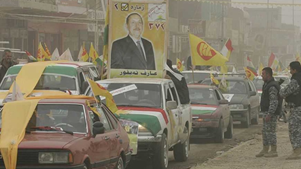 IRAQ Iraqi policemen look at supporters waving the semi-autonomous region of Kurdistan and Kurdistan Democratic Party (KDP) flags during a sand storm at a rally ahead of March 7 parliamentarian elections in Kirkuk, 250 km (150 miles) north of Baghdad, February 23, 2010. Picture taken February 23, 2010. REUTERS/Ako Rasheed (IRAQ - Tags: POLITICS ELECTIONS)