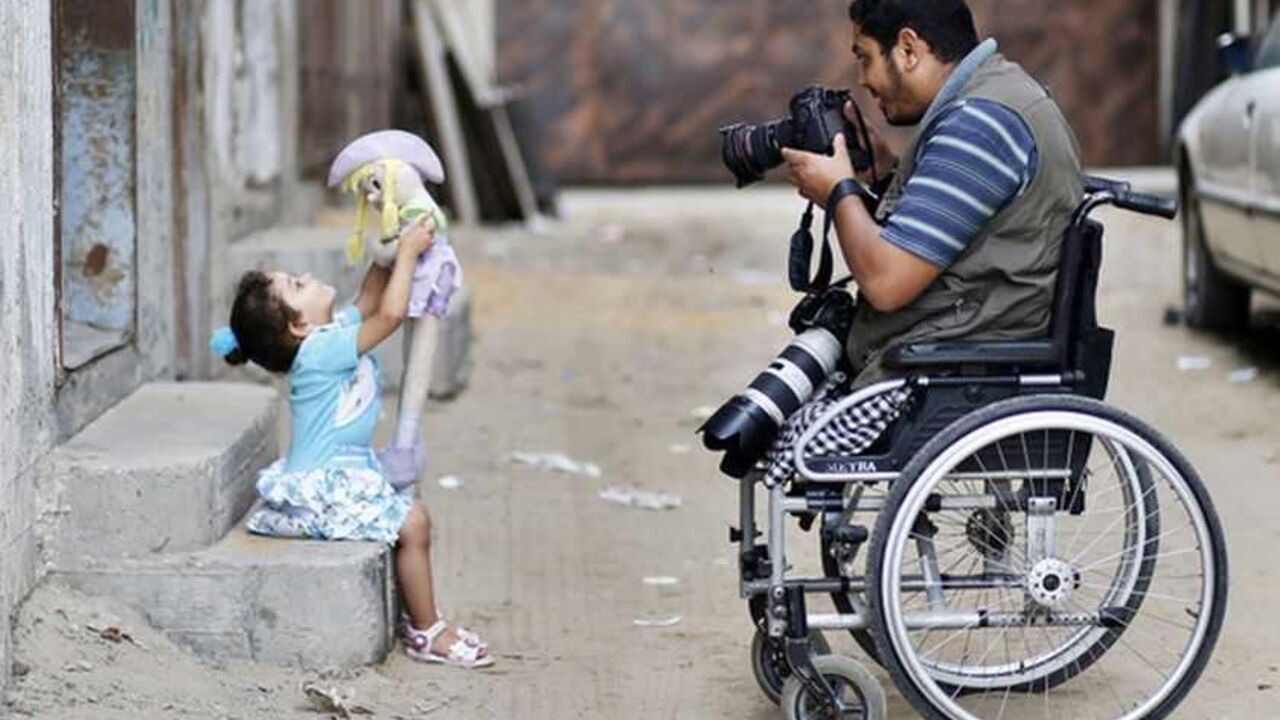 A wheelchair-bound Palestinian freelance photographer takes pictures of his daughter outside his home in Gaza City Wheelchair-bound Palestinian freelance photographer Moamen Qreiqea takes pictures of his daughter outside his home in Gaza City October 1, 2012. Qreiqea, 25, lost both his legs in an Israeli air strike in 2008 while taking pictures east of Gaza. The father of two is determined to continue his career despite his disability. REUTERS/Suhaib Salem (GAZA - Tags: MEDIA SOCIETY)