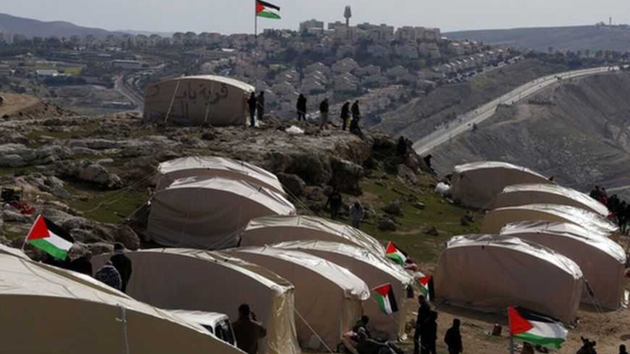 Palestinians, together with Israeli and foreign activists, stand near newly-erected tents in an area known as E1, near Jerusalem Palestinians, together with Israeli and foreign activists, stand near newly-erected tents in an area known as E1, near Jerusalem January 12, 2013. Palestinians from villages in the occupied West Bank near Jerusalem pitched tents on Friday on the land Israel has earmarked for a new urban settlement, looking to preserve the area for an independent Palestinian state. REUTER/Baz Ratner (WEST BANK - Tags: POLITICS CIVIL UNREST BUSINESS CONSTRUCTION)