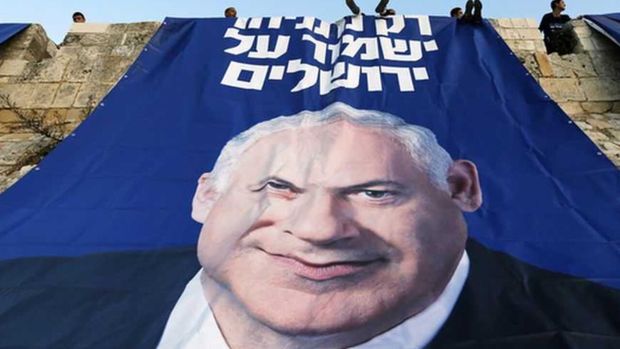 Likud-Yisrael Beitenu activists sit atop a wall surrounding Jerusalem's Old City after they hung a campaign banner depicting Israel's Prime Minister Netanyahu Likud-Yisrael Beitenu activists sit atop a wall surrounding Jerusalem's Old City after they hung a campaign banner depicting Israel's Prime Minister Benjamin Netanyahu January 20, 2013. Netanyahu said on Saturday a country with as many enemies as Israel cannot afford a weak ruling party, after polls ahead of Tuesday's parliamentary election showed a slide in his support. The banner reads "Only Netanyahu will protect Jerusalem". REUTERS/Ronen Zvulun (JERUSALEM - Tags: POLITICS ELECTIONS TPX IMAGES OF THE DAY