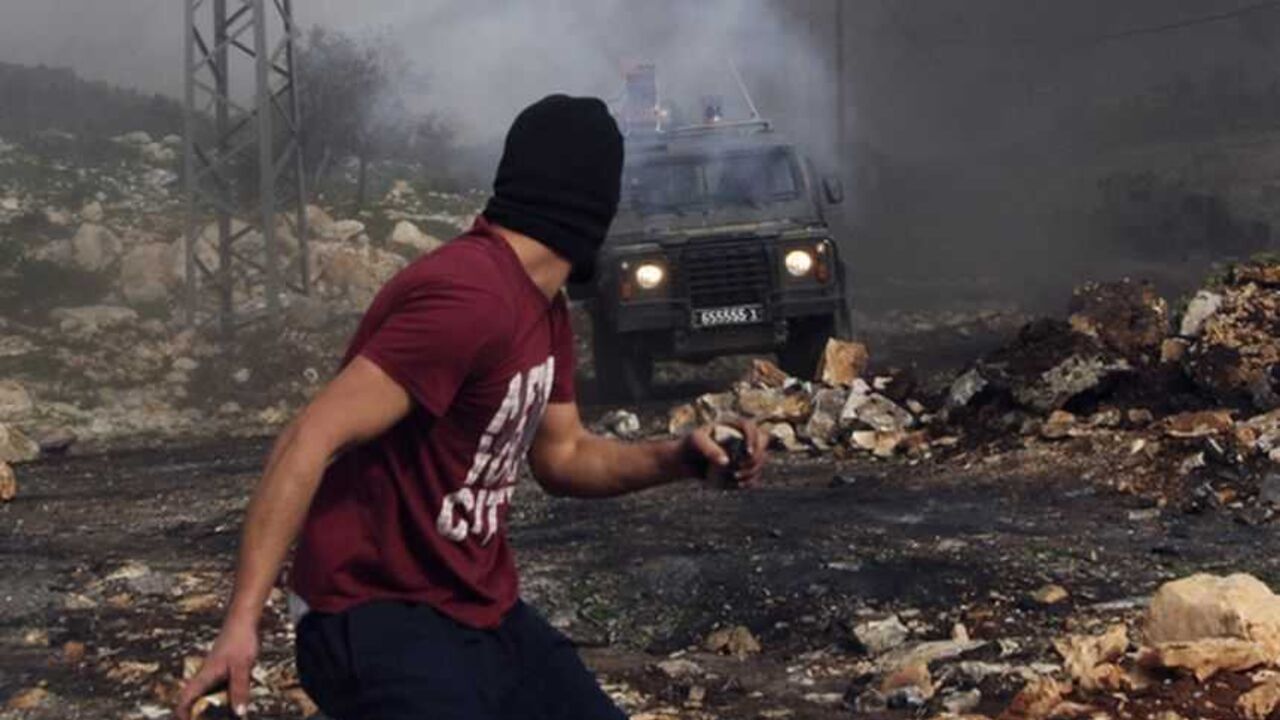 Stone-throwing Palestinian protester runs near an Israeli border police vehicle during clashes near Nablus A stone-throwing Palestinian protester runs near an Israeli border police vehicle during clashes at a weekly protest against the nearby Jewish settlement of Kdumim, in the West Bank village of Kfar Kadum, near Nablus January 25, 2013. REUTERS/Abed Omar Qusini (WEST BANK - Tags: POLITICS CIVIL UNREST) - RTR3CXSG