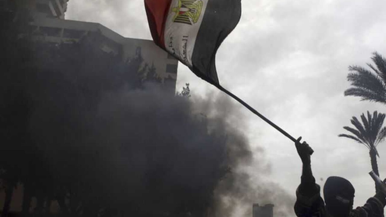 A protester opposing Egyptian President Mohamed Mursi gestures with a national flag at riot police during clashes along Qasr Al Nil bridge leading to Tahrir Square in Cairo A protester opposing Egyptian President Mohamed Mursi gestures with a national flag at riot police during clashes along Qasr Al Nil bridge leading to Tahrir Square in Cairo January 28, 2013. A man was shot dead on Monday in a fifth day of violence in Egypt that has killed 50 people and prompted the Islamist president to declare a state of emergency in an attempt to end a wave of unrest sweeping the Arab world's biggest nation. REUTERS/Amr Abdallah Dalsh (EGYPT - Tags: POLITICS CIVIL UNREST TPX IMAGES OF THE