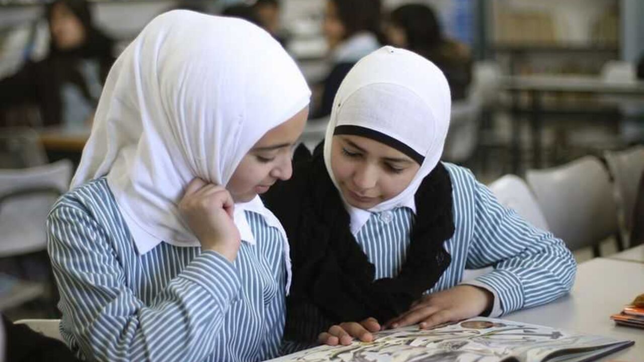 Palestinian students share a schoolbook while studying in the school library in the West Bank city of Ramallah Palestinian students share a schoolbook while studying in the school library in the West Bank city of Ramallah February 4, 2013. Israelis and Palestinians depict each other in schoolbooks as an enemy and largely deny their adversary's history and existence, according to a U.S. government-funded study published on Monday. REUTERS/Mohamad Torokman (WEST BANK - Tags: POLITICS EDUCATION) - RTR3DCH6
