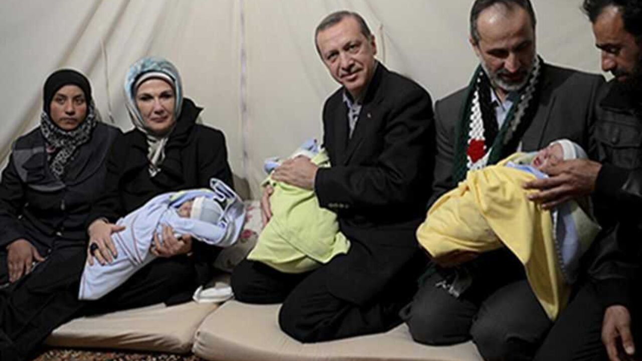 SYRIA-CRISIS/ERDOGAN Turkish Prime Minister Tayyip Erdogan (C) and his wife Emine Erdogan (2nd L) pose with Syrian refugee triplet baby brothers whose names are Recep, Tayyip and Erdogan as they visit a refugee camp near Akcakale border crossing on the Turkish-Syrian border, southern Sanliurfa province, December 30, 2012, as they are flanked by the parents of the babies and head of the internationally-recognised, opposition Syrian National Council, Moaz al-Khatib (2nd R). REUTERS/Kayhan Ozer/Prime Minister's Press Office/Handou