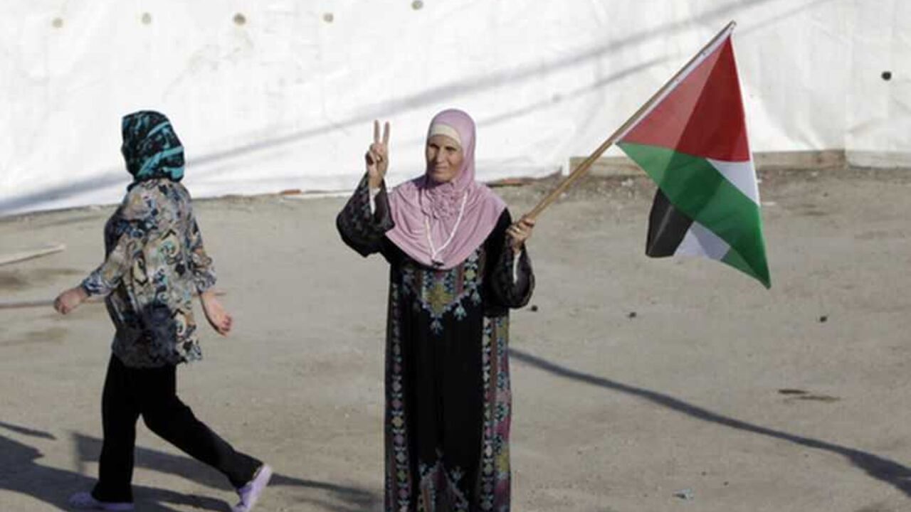 Rukia, the mother-in-law of Palestinian prisoner Ibtisam Issawi, holds a flag outside her home in East Jerusalem Rukia, the mother-in-law of Palestinian prisoner Ibtisam Issawi, holds a flag outside her home in the Arab East Jerusalem neighbourhood of Jabal Mukaber October 17, 2011, as the family prepares for the release of Issawi in a prisoner swap that is expected to take place on Tuesday. Israel and Gaza's Hamas Islamist rulers have agreed to swap 1,027 Palestinian prisoners in return for Israeli soldier Gilad Shalit, who has been held captive in Gaza since 2006. REUTERS/Ammar Awad (JERUSALEM - Tags: POLITICS CIVIL