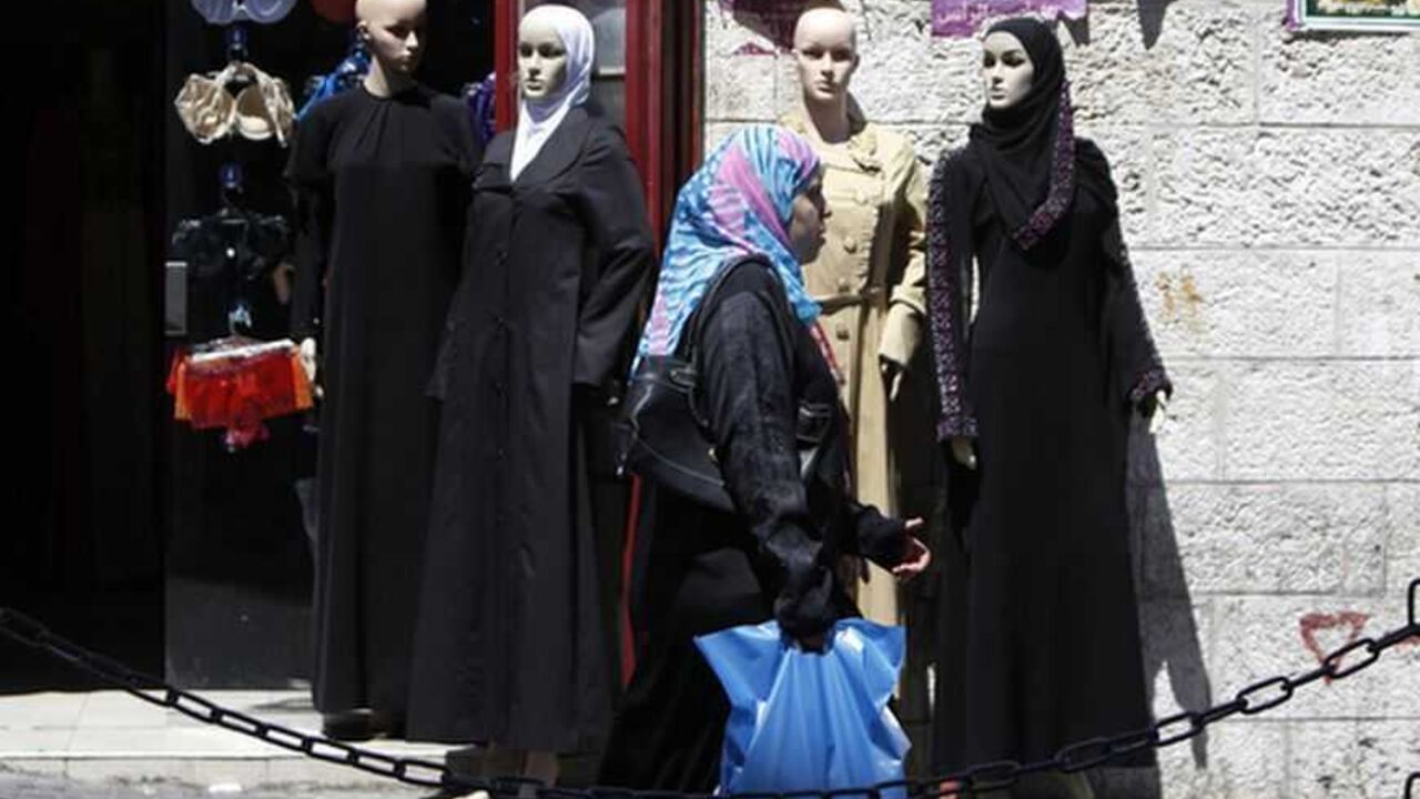A Palestinian woman walks past a clothing store in the West Bank city of Ramallah A Palestinian woman walks past a clothing store in the West Bank city of Ramallah September 4, 2012. Palestinian dreams of building a powerful economy to speed their drive towards independence could soon be plunged into darkness. The cash-strapped government of the occupied West Bank, the Palestinian Authority, is so behind with its bills that an Israeli electricity supplier has threatened to cut the power unless they pay outstanding debt of almost $80 million. Picture taken September 4, 2012. To match Feat