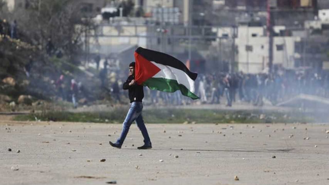 A Palestinian protester holds a flag during clashes between protesters and Israeli border policemen near Ramallah A Palestinian protester holds a flag during clashes between protesters and Israeli border policemen outside Israel's Ofer prison near the West Bank city of Ramallah February 15, 2013. Clashes broke out on Friday between Palestinian stone-throwers and Israeli troops following a protest calling for the release of hunger-striking Palestinian prisoners held in Israeli jails. REUTERS/Mohamad Torokman (WEST BANK - Tags: POLITICS CIVIL UNREST) - RTR3DU35