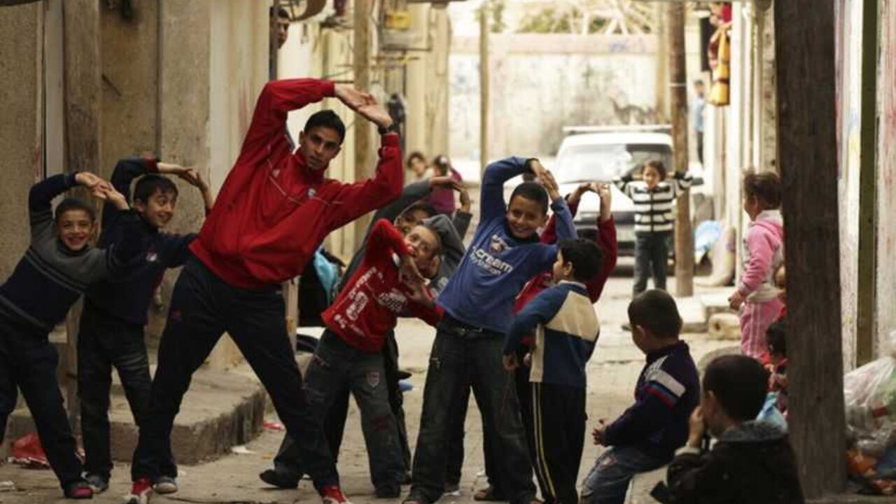 Gaza runner Bahaa al-Farra stretches during a training session as children mimic him while posing for the camera in Shati refugee camp in Gaza City Gaza runner Bahaa al-Farra stretches during a training session as children mimic him while posing for the camera in Shati refugee camp in Gaza City March 25, 2012. The 19-year-old trains for three hours a day in Gaza's Yarmouk soccer stadium, along the dusty streets and on the beach in well worn trainers that were donated to the Palestine Olympic Committee by wealthy Gulf state, Qatar, as he prepares to race at the London Olympics. Picture taken March 25, 2012. REUTERS/ Mohammed Salem (GAZA - Tags: SPORT