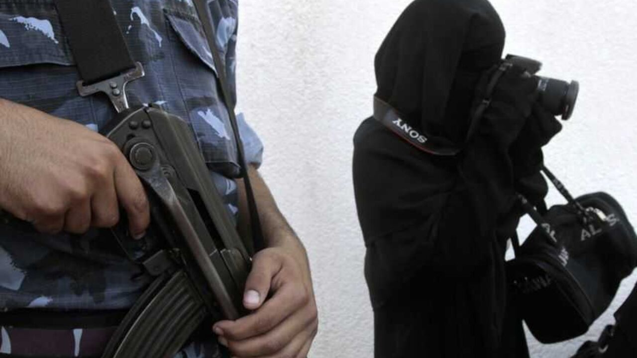 Member of Hamas security force stands guard as woman takes pictures during demonstration in solidarity with al-Aqsa mosque in Gaza City A member of the Hamas security force stands guard as a woman takes pictures during a demonstration in solidarity with al-Aqsa mosque, organized by the Hamas movement in Gaza City September 28, 2009. Israeli police and Palestinian protesters clashed at the Dome of the Rock in the Old City of Jerusalem on Sunday morning. Palestinians said the clash was triggered by religious Israeli Jews trying to enter the holy site, while Israeli police said it began when religious Palestinians angered by immodestly dressed