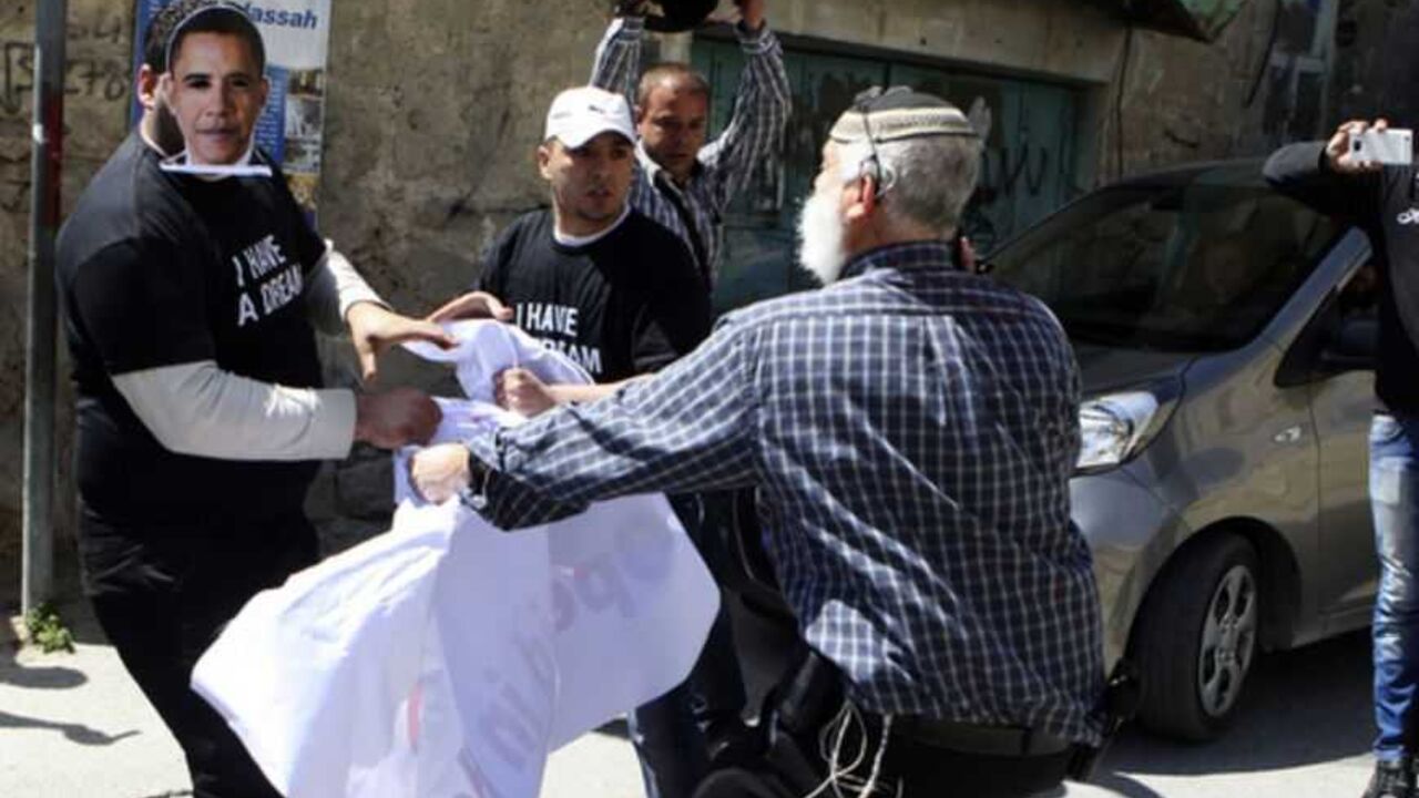 An Israeli settler and Palestinians demonstrators, one wearing a mask depicting U.S. President Obama scuffle during a protest in Hebron An Israeli settler (front) and Palestinians demonstrators, one wearing a mask depicting U.S. President Barack Obama, scuffle during a protest against the continued closure by the Israeli army of Shuhada street to Palestinians in the West Bank city of Hebron March 20, 2013. Obama arrived in Israel on Wednesday without any new peace initiative to offer disillusioned Palestinians and facing deep Israeli doubts over his pledge to prevent a nuclear-armed Iran. REUTERS/ Mussa Qawasma (WEST BANK - Tags: POLITICS C
