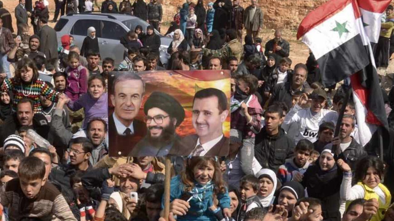People chant slogans while holding Syrian national flags and a placard during a protest in Aleppo People chant slogans while holding Syrian national flags and a placard (C) with images of former Syrian President Hafez al-Assad (L), Syria's President Bashar al-Assad (R) and Lebanon's Hezbollah leader Sayyed Hassan Nasrallah during a protest in support of Bashar al-Assad in Aleppo March 9, 2013. REUTERS/George Ourfalian (SYRIA - Tags: CIVIL UNREST MILITARY POLITICS CONFLICT) - RTR3ERVA