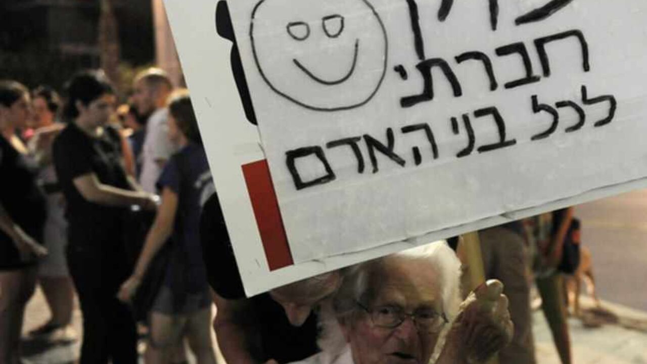 An Israeli Holocaust survivor holds a si An Israeli Holocaust survivor holds a sign calling for social justice for all human beings, during a demonstration in Tel Aviv against racism and the government's policy regarding African migrants on July 28, 2012. Israel's government is planning tough new legislation against migrants, with the cabinet on July 22, approving stiff fines or six months in jail for illegal residents sending money home. AFP PHOTO/DAVID BUIMOVITCH (Photo credit should read DAVID BUIMOVITCH/AFP/GettyImages)