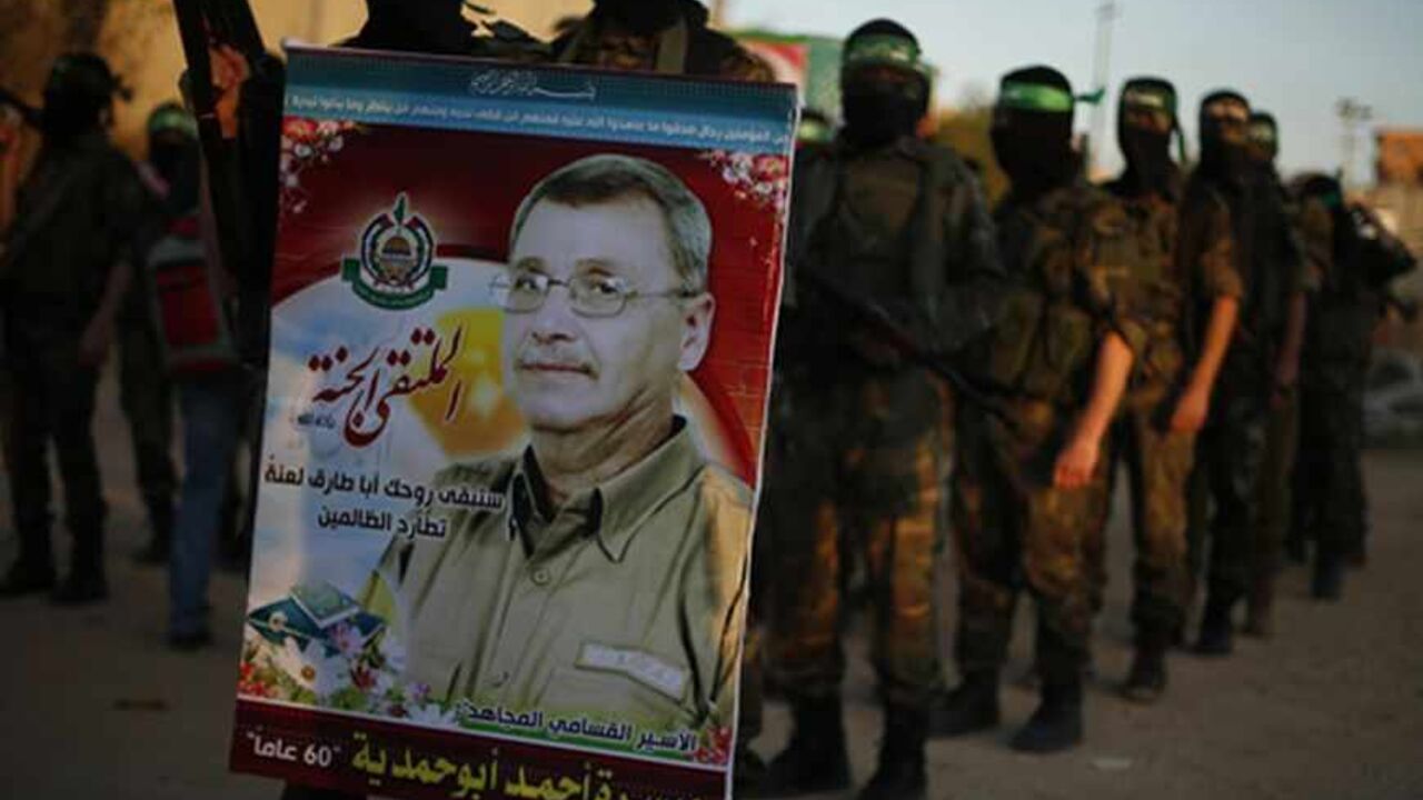 PALESTINIANS-ISRAEL/PRISONER A Hamas militant holds a poster of Maysara Abu Hamdeya before a protest in the northern Gaza Strip April 2, 2013. Israeli prison guards fired tear gas to quell disturbances by Palestinian inmates on Tuesday after a prisoner serving a life sentence over an attempt to bomb an Israeli cafe died of cancer. Maysara Abu Hamdeya's death threatened to raise tensions in the Israeli-occupied West Bank, where Palestinians, who view jailed brethren as heroes in a fight for statehood, have held several protests in recen