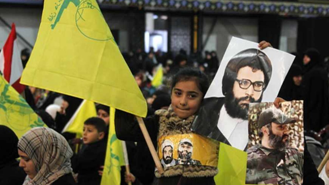 LEBANON/ A child waves a Hezbollah flag as she holds pictures of martyrs as Hezbollah leader Sayyed Hassan Nasrallah addresses his supporters during a rally to commemorate Martyrs' Day in Beirut, February 16, 2013. REUTERS/Sharif Karim (LEBANON - Tags: POLITICS) - RTR3DVC2