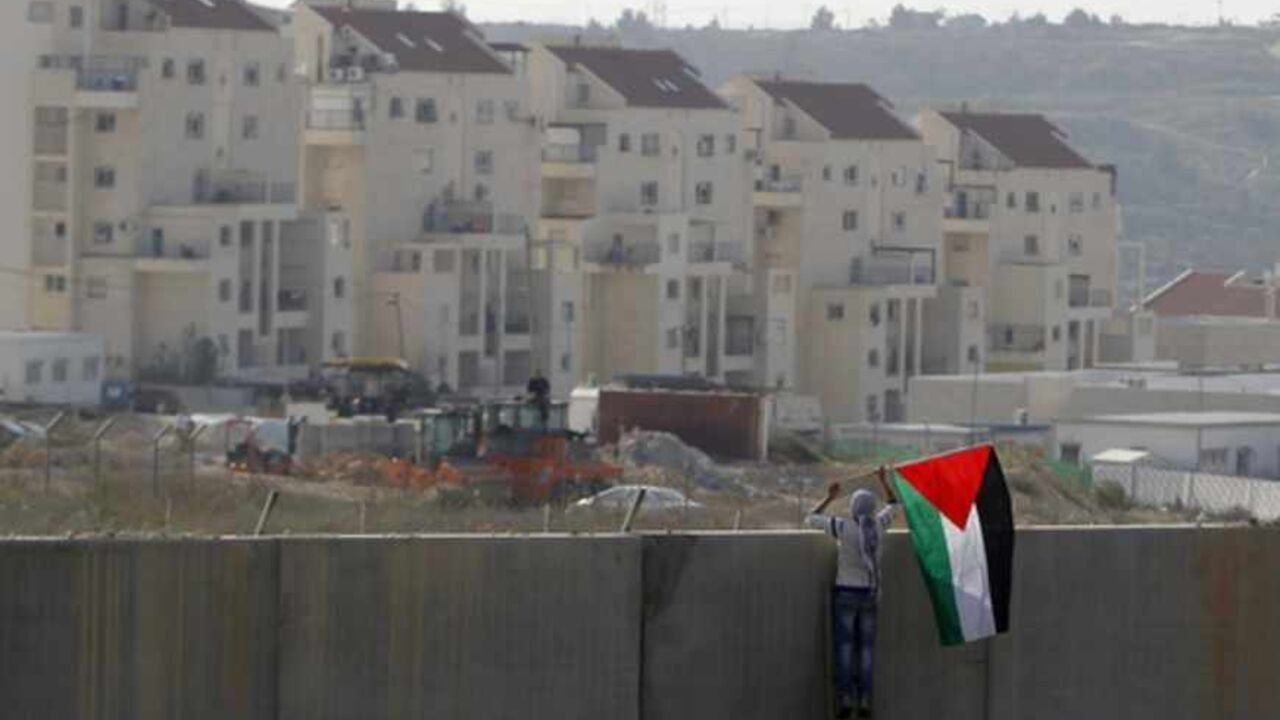 A Palestinian protester places a flag on the controversial Israeli barrier during clashes with Israeli security officers near Ramallah A Palestinian protester places a flag on the controversial Israeli barrier during clashes with Israeli security officers (unseen) after a rally marking the 48th anniversary of the founding of the Fatah movement, in the West Bank village of Bilin near Ramallah, January 4, 2013. REUTERS/Ammar Awad (WEST BANK - Tags: POLITICS CIVIL UNREST TPX IMAGES OF THE DAY) - RTR3C3OA