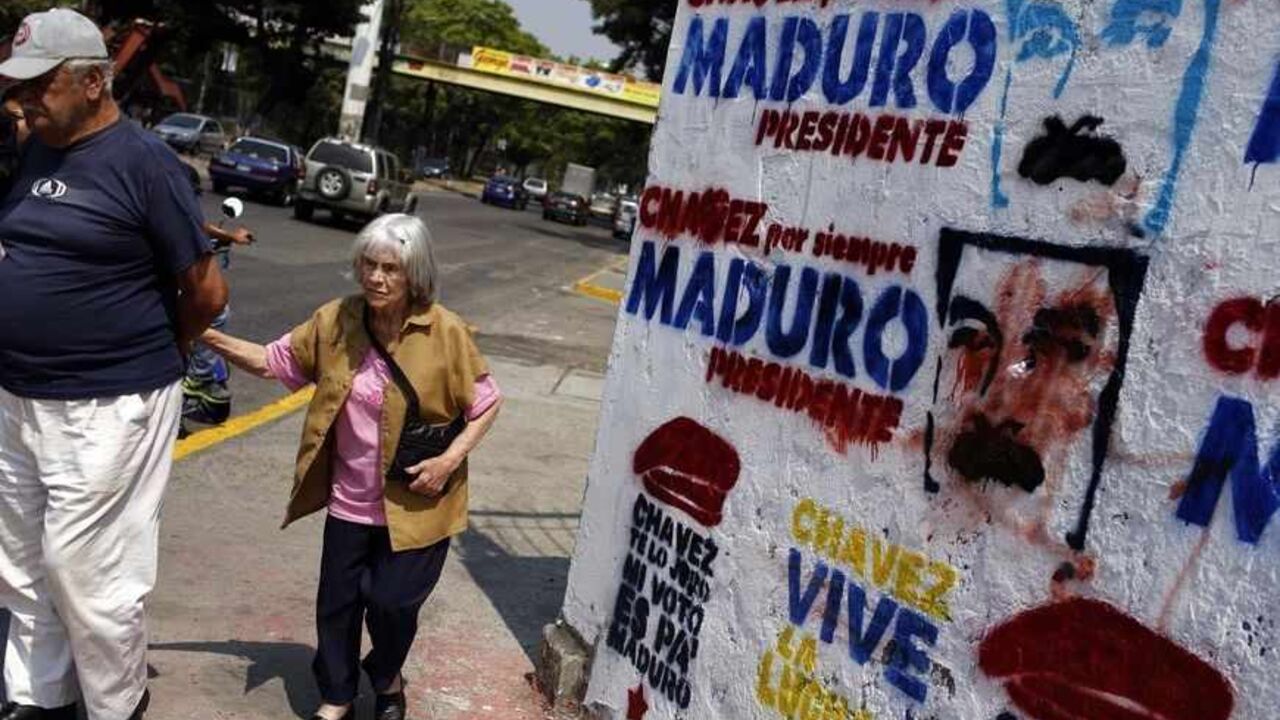 VENEZUELA-ELECTION/ A couple walks past a wall with graffiti promoting Venezuela's acting President and presidential candidate Nicolas Maduro in Caracas April 12, 2013. The late Hugo Chavez's self-declared socialist revolution will be put to the test at a presidential election on Sunday that pits Maduro, his chosen successor against a younger rival promising change in the nation he polarized. The signs on the wall read, "Chavez forever, Maduro President" (top), "Chavez I swear to you, my vote is for Maduro" (bottom L) and "Cha