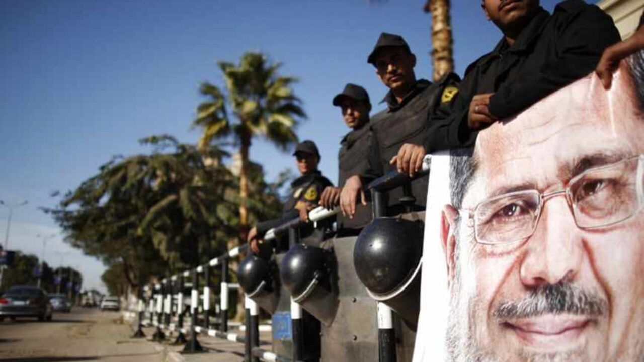 Policemen stand guard near a poster outside the constitutional court put up by supporters of Egyptian President Mohamed Mursi as they stage a sit-in, in Cairo Policemen stand guard near a poster outside the constitutional court put up by supporters of Egyptian President Mohamed Mursi as they stage a sit-in, in Cairo December 23, 2012. Egyptian President Mohamed Mursi will have little time to savour victory in pushing through a new constitution as it may have cost the Islamist leader broader support for urgent austerity measures needed to fix the creaking economy. REUTERS/Khaled Abdullah (EGYPT) - RTR3BUY2