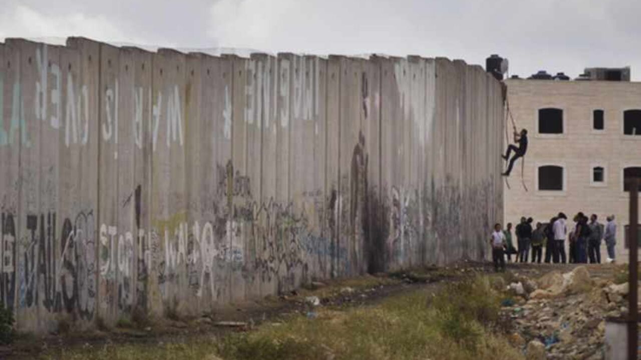 168949961US030_PALESTINIANS RAMALLAH, WEST BANK - MAY 15: A Palestinian youth climbs Israel's separation wall during clashes with the Israeli army during Nakba day on May 15, 2013 near the Qalandia checkpoint at the outskirts of Ramallah, the West Bank. Palestinians mark Israel's establishment in 1948 with 'Nakba' or 'catastrophe' day on May 15, to remember the thousands of Palestinians who fled or were expelled during the creation of the Jewish state and the subsequent war. (Photo by Uriel Sinai/Getty Images)