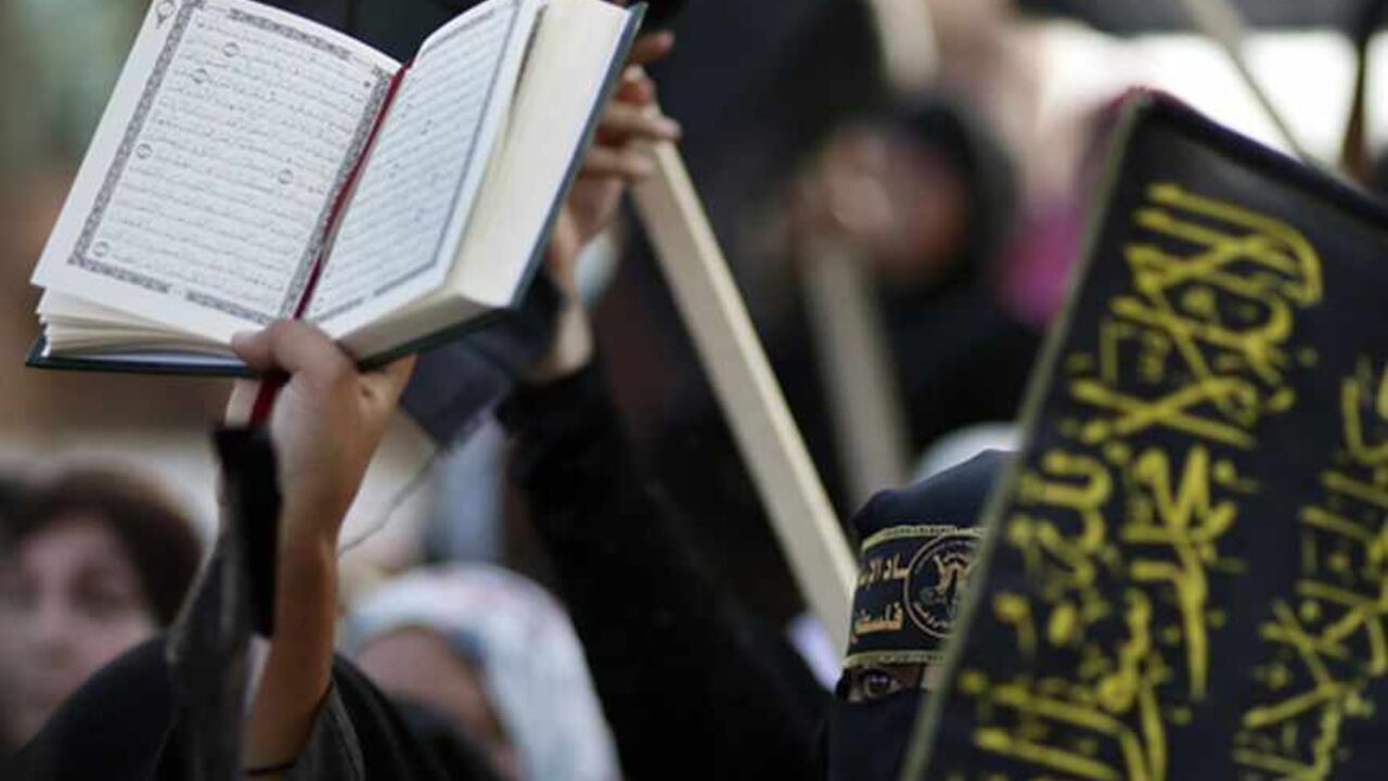 PALESTINIANS/ A woman holds a copy of Koran during a rally marking the 25th anniversary of foundation of the Islamic Jihad movement in Gaza City October 4, 2012. REUTERS/Suhaib Salem (GAZA - Tags: POLITICS CIVIL UNREST ANNIVERSARY RELIGION) - RTR38SLV