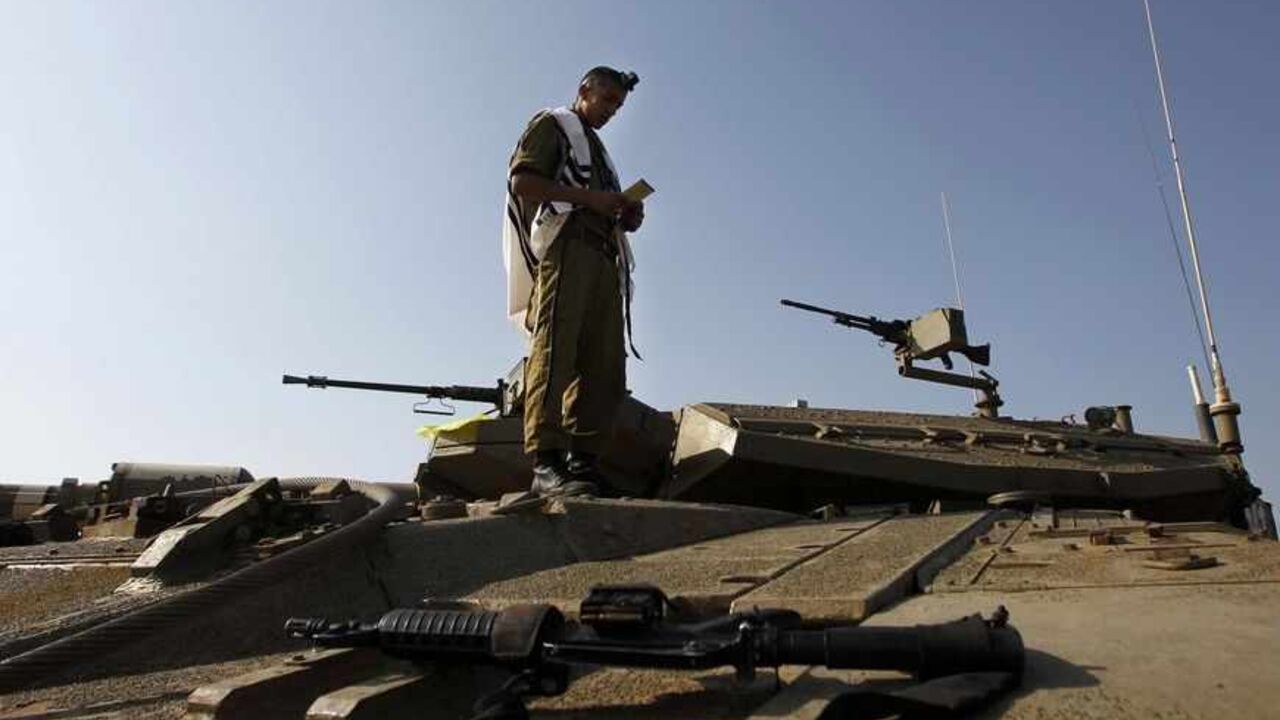 SYRIA-CRISIS/ISRAEL An Israeli soldier prays atop a tank close to the ceasefire line between Israel and Syria on the Israeli occupied Golan Heights May 6, 2013. Israel sought to persuade Syrian President Bashar al-Assad on Monday that its recent air strikes around Damascus did not aim to weaken him in the face of a more than two-year-old rebellion. REUTERS/Baz Ratner (ISRAEL - Tags: POLITICS MILITARY) - RTXZC75