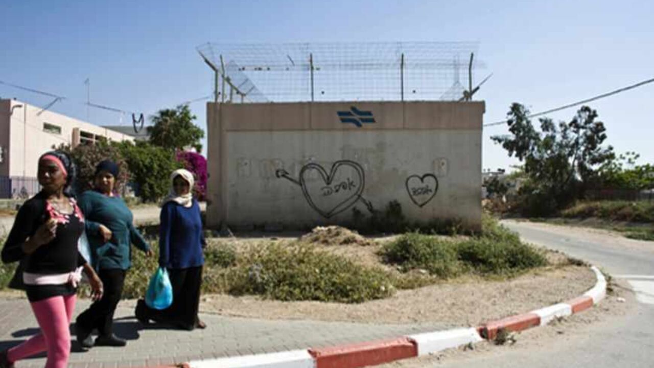 ISRAEL-ARABS/CRIME Women walk past a Hebrew graffiti that reads "Love" in the "Train" neighbourhood in Lod May 15, 2012. The backstreets of Lod, a mixed Arab-Jewish city just 20 minutes from the tree-lined boulevards of Tel Aviv, reveal a seamy underside of Israel that few visitors get to see, tucked away behind Ben Gurion airport off the main highway to Jerusalem and the occupied West Bank. Picture taken May 15, 2012. To match Feature ISRAEL-ARABS/CRIME REUTERS/Nir Elias (ISRAEL - Tags: SOCIETY) - RTR32TYI