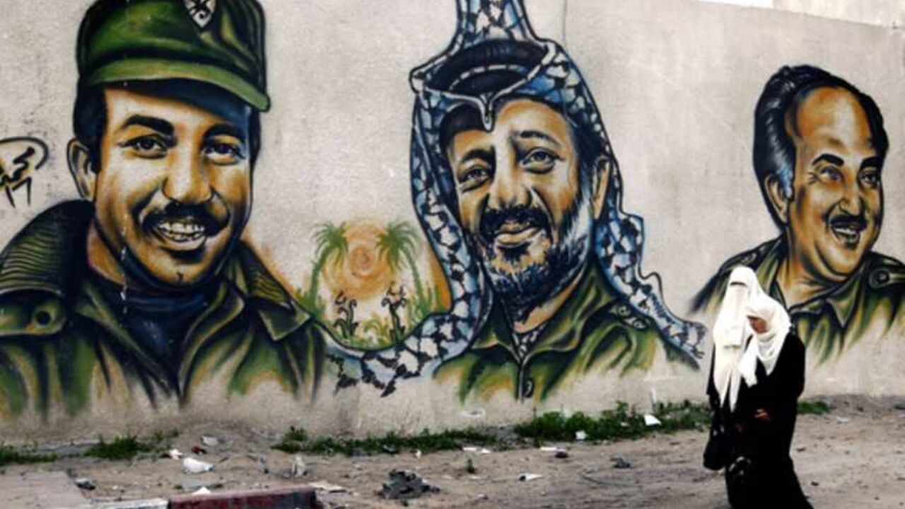 Palestinian women walk by the walls of the destroyed Hamas headquarters compound in Gaza January 24, 2009. The Hamas headquarters was repeatedly bombed during Israel's devastating three-week war. On the background are portraits of (L-R)  Khalil Al Wazir (second in command in Fatah movement, Yassir Arafat (Late Palestinian President) and Salah Khalaf  (co-founder of the Palestinian Liberation Organization), all deceased.    REUTERS/Yannis Behrakis (GAZA) - RTR23TCK