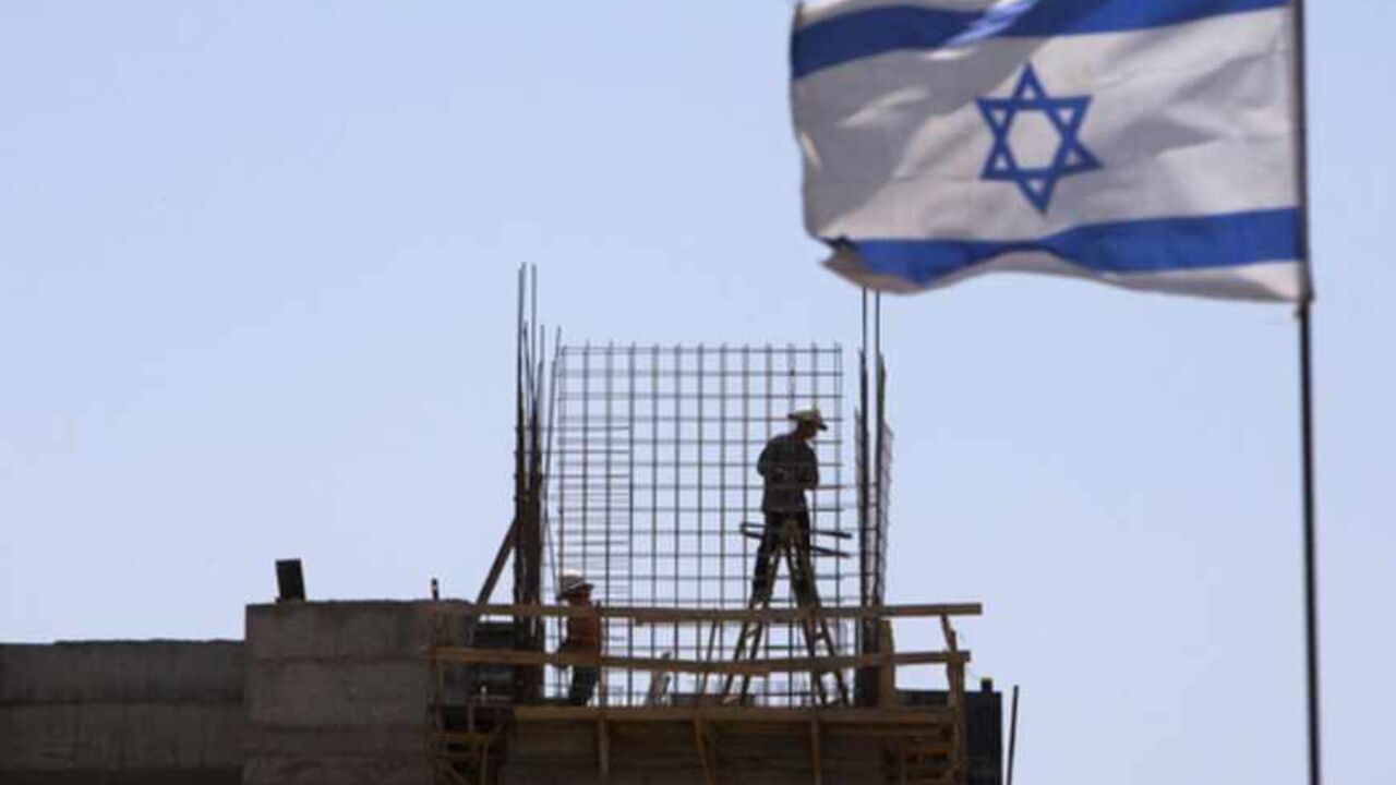An Israeli flag is seen as labourers work on a construction site in a Jewish settlement near Jerusalem An Israeli flag is seen as labourers work on a construction site in a Jewish settlement near Jerusalem known to Israelis as Har Homa and to Palestinians as Jabal Abu Ghneim May 7, 2013. Prime Minister Benjamin Netanyahu has quietly curbed new building projects in Jewish settlements, an Israeli watchdog group and media reports said on Tuesday, in an apparent bid to help U.S. efforts to revive peace talks with the Palestinians. REUTERS/Ronen Zvulun (BUSINESS CONSTRUCTION POLITICS) - RTXZDIA
