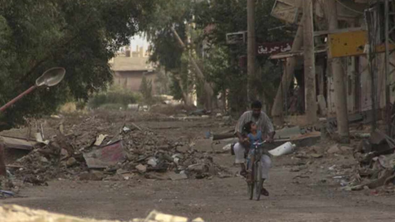 SYRIA-CRISIS/ A man rides a bicycle with a child along a damaged street full of debris in Deir al-Zor May 19, 2013. Picture taken May 19, 2013. REUTERS/Khalil Ashawi (SYRIA - Tags: CONFLICT SOCIETY) - RTXZTR4