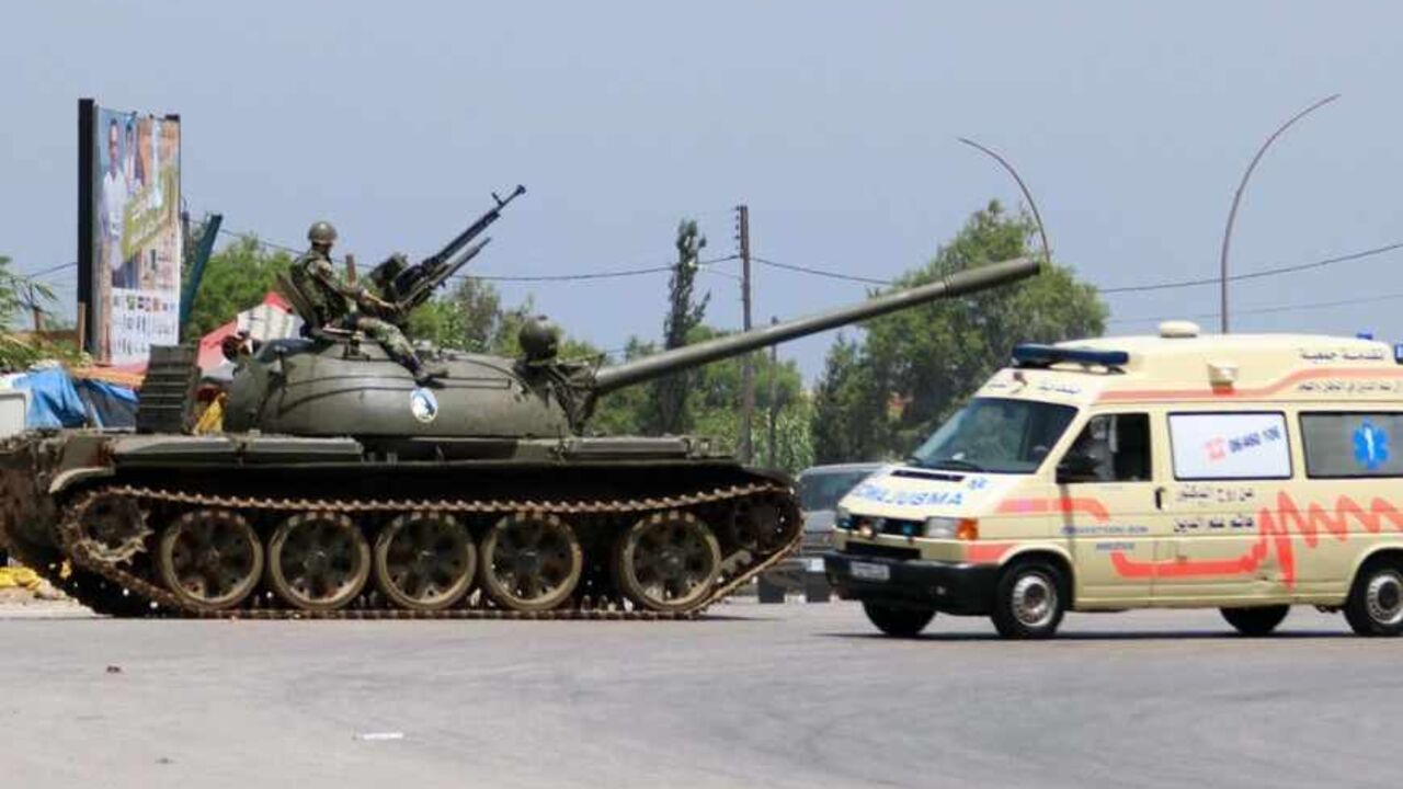 SYRIA-CRISIS-LEBANON A Lebanese army soldier is seen atop his tank as an ambulance travels past in Tripoli May 20, 2013. Three people have been killed and about 40 wounded in two days of fighting in Lebanon's northern city of Tripoli, security sources said on Monday, as sectarian violence spilled over from the civil war in Syria. REUTERS/Omar Ibrahim (LEBANON - Tags: POLITICS CIVIL UNREST MILITARY) - RTXZTWK