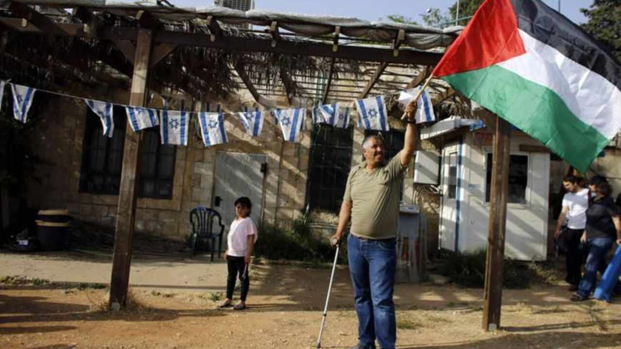 Palestinian protester waves a Palestinian flag in the Sheikh Jarrah neighborhood of East Jerusalem during a weekly demonstration against Jewish settlements A Palestinian protester waves a Palestinian flag in the Sheikh Jarrah neighborhood of East Jerusalem May 17, 2013, during a weekly demonstration against Jewish settlements and the possible eviction of a Palestinian family from their home. REUTERS/Ammar Awad (JERUSALEM - Tags: POLITICS CIVIL UNREST) - RTXZQQH