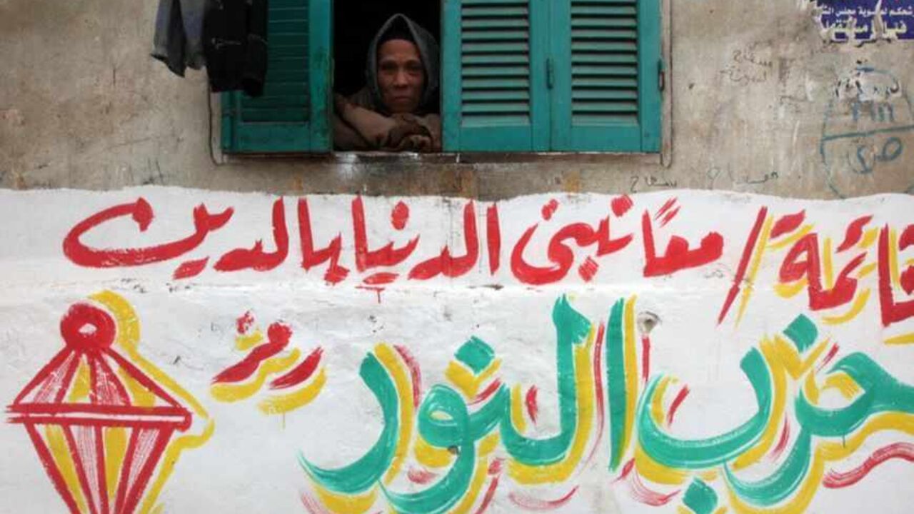 A woman looks through her window above an electoral slogan for Salafi political party Al-Nour in Toukh A woman looks through her window above an electoral slogan for Salafi political party Al-Nour that reads, "Together hand in hand we build the country through religion" , outside a polling station in Toukh, El-Kalubia governorate, about 25 km (16 miles) northeast of Cairo January 3, 2012. Egyptians voted in the third round of a parliamentary election on Tuesday that has so far handed Islamists the biggest share of seats in an assembly that will be central in the planned transition from army rule. REUTERS/Amr