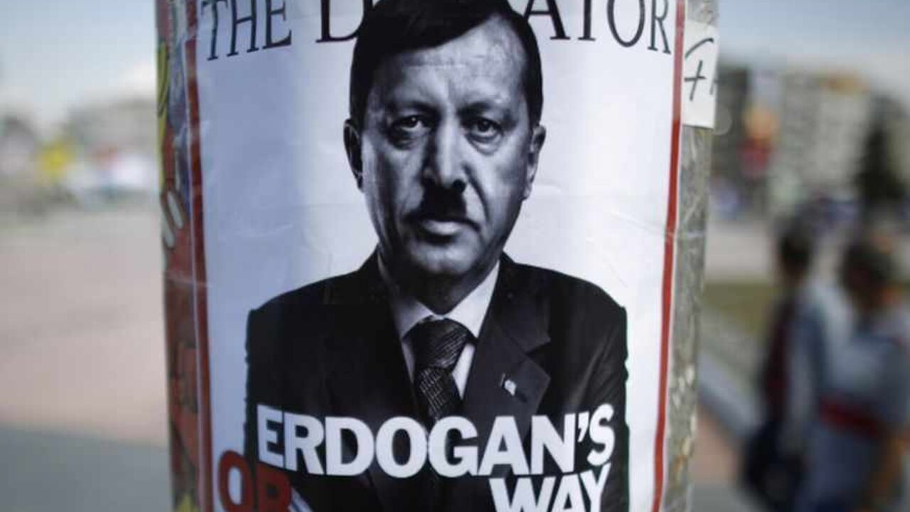 People walk past a poster depicting Turkish Prime Minister Tayyip Erdogan that has been pasted by demonstrators at Taksim Square in Istanbul People walk past a poster depicting Turkish Prime Minister Tayyip Erdogan that has been pasted by demonstrators at Taksim Square in Istanbul June 5, 2013. Protesters clashed with police across Turkey overnight despite an apology for police violence from the deputy prime minister designed to halt an unprecedented wave of protest against Prime Minister Tayyip Erdogan. Pro-government newspapers signalled a softening of Ankara's line in the absence of Erdogan, who flew off on a state visit to north Africa on Mo