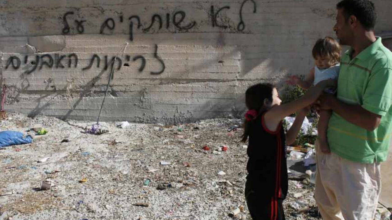 Palestinians stand next to graffiti sprayed near their house in Beit Hanina in East Jerusalem Palestinians stand next to graffiti sprayed on a wall near their house in the Arab neighborhood of Beit Hanina in East Jerusalem June 24, 2013. Graffiti was sprayed and tires were slashed on 21 cars overnight in Beit Hanina in what appeared to be another in a series of "Price Tag" attacks by suspected Jewish militants. Police opened an investigation. The graffiti reads: We will not remain silent in the face of the stone-throwing". REUTERS/Ammar Awad (JERUSALEM - Tags: POLITICS CIVIL UNREST) - RTX10YSG