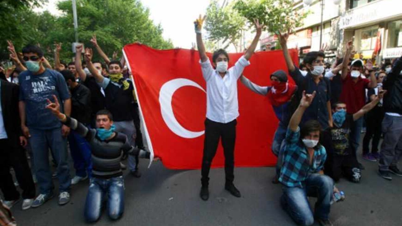 TURKEY-POLITICS-DEMO TuTurkish protesters holding a Turkish flag demonstrate on the main city square, Kizilay, in the Turkish capital Ankara on June 3, 2013. rkish Prime Minister Recep Tayyip Erdogan on Monday rejected talk of a "Turkish Spring", shrugging off mass protests against his government as medics reported the first death in days of violence. Rallies started there last week initially in protest at plans to redevelop the adjacent Gezi Park, a rare green spot in central Istanbul, and quickly spread, inflamed by anger at