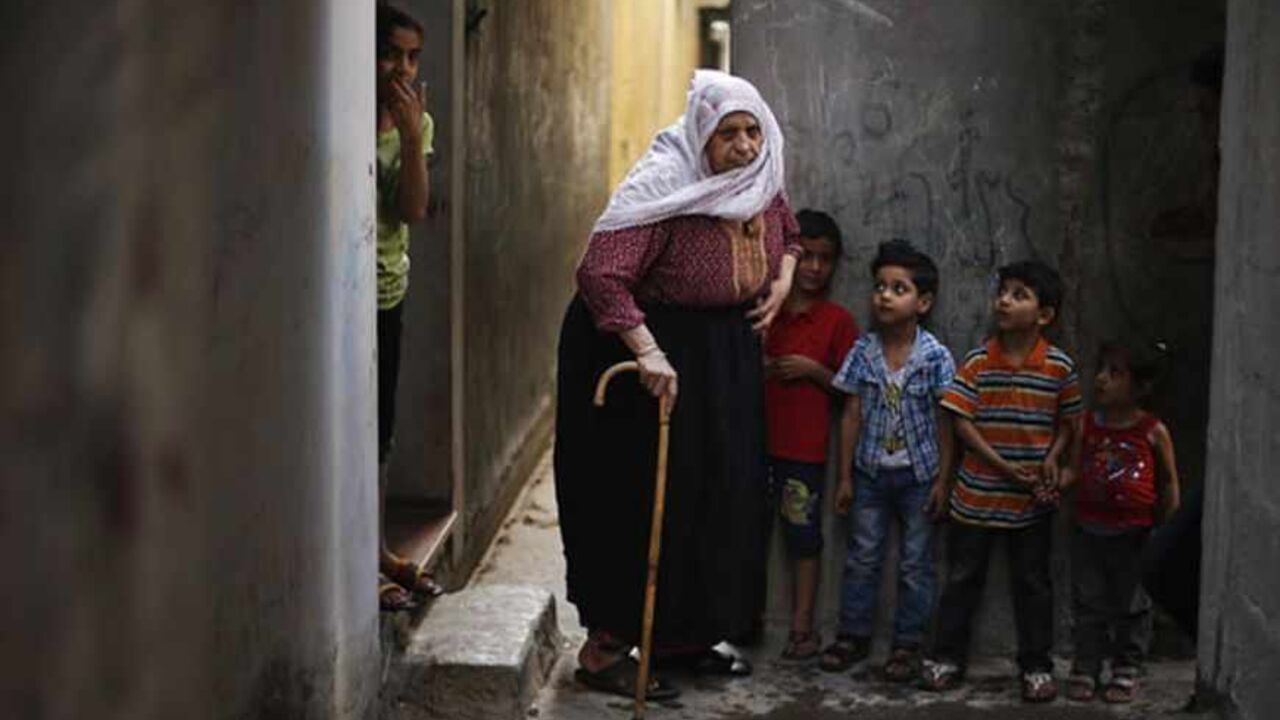 PALESTINIANS-ISRAEL/ Palestinian refugee Fatem Redwan, 76, walks next to her grandchildren in the narrow alleys of Jabalya refugee camp at the northern Gaza Strip May 14, 2013. Redwan said she was 11 years old when she was forced out of her native town with her family to Gaza Strip. Palestinians will mark "Nakba" (Catastrophe) on May 15 to commemorate the expulsion or fleeing of some 700,000 Palestinians from their homes in the war that led to the founding of Israel in 1948. REUTERS/Suhaib Salem (GAZA - Tags: CIVIL UNREST POLI