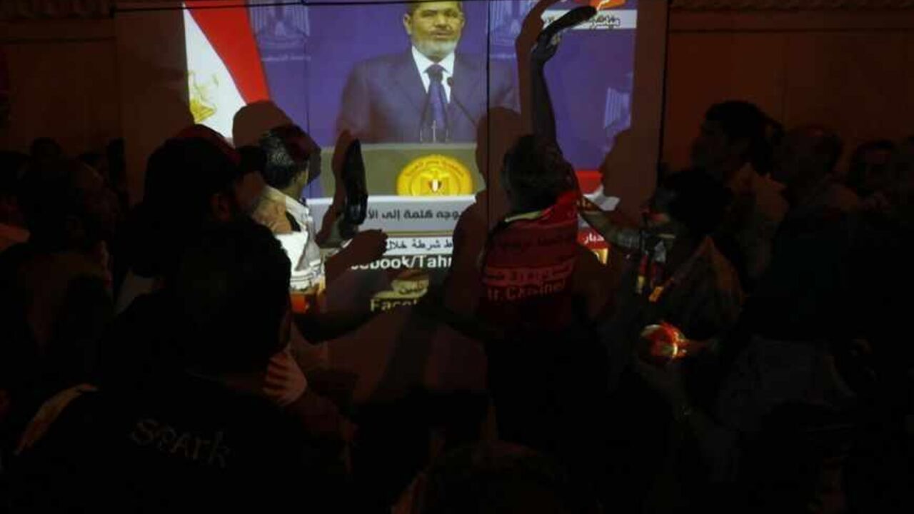 Protesters opposing Egyptian President Mohamed Mursi shout slogans and hit the screen with their shoes as he speaks to the nation, in front of the Ministry of Defense in Cairo June 26, 2013. Mursi blamed "enemies of Egypt" for paralyzing its new democracy in a speech on Wednesday that criticized street protests ahead of mass rallies against Islamist rule this weekend. REUTERS/Amr Abdallah Dalsh  (EGYPT - Tags: POLITICS CIVIL UNREST) - RTX112D1