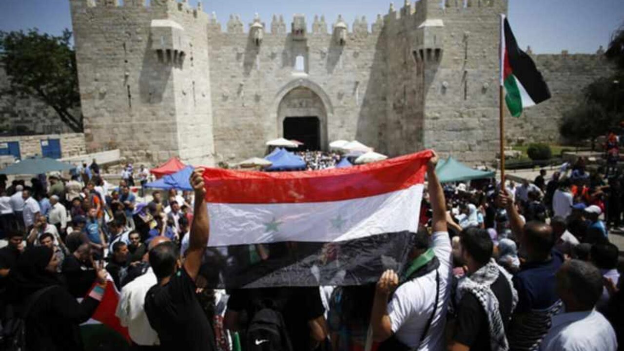Palestinian protesters hold the Syrian national flag during a demonstration outside Damascus Gate in Jerusalem's Old City Palestinian protesters hold the Syrian national flag to show their support for Syrian President Bashar al-Assad during a demonstration outside Damascus Gate in Jerusalem's Old City June 7, 2013. A few dozen protesters took part in the demonstration after Friday prayers to mark the 46th anniversary of the 1967 Middle East war, when Israel captured East Jerusalem, the Gaza Strip, the West Bank and Golan Heights. REUTER/Baz Ratner (JERUSALEM - Tags: CIVIL UNREST POLITICS) - RTX10F5Y