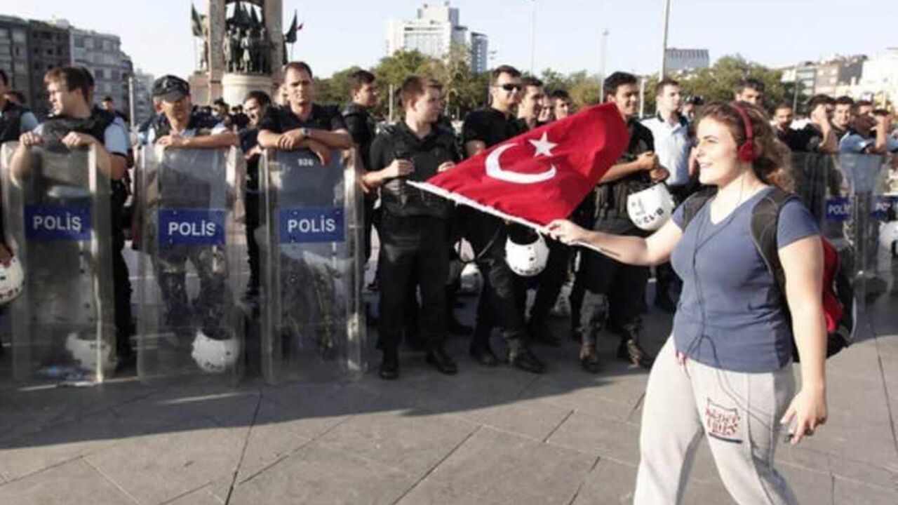 An anti-government protester waves a Turkish flag in front of riot police during a demonstration at Taksim square An anti-government protester waves a Turkish flag in front of riot police during a demonstration at Taksim square in central Istanbul June 25, 2013. Turkish anti-terrorism police detained 20 people in raids in the capital Ankara on Tuesday in connection with weeks of anti-government protests across the country, media reports said. The unrest began at the end of May when police used force against campaigners opposed to plans to redevelop a central Istanbul park. The protest spiralled into broader demonstrati
