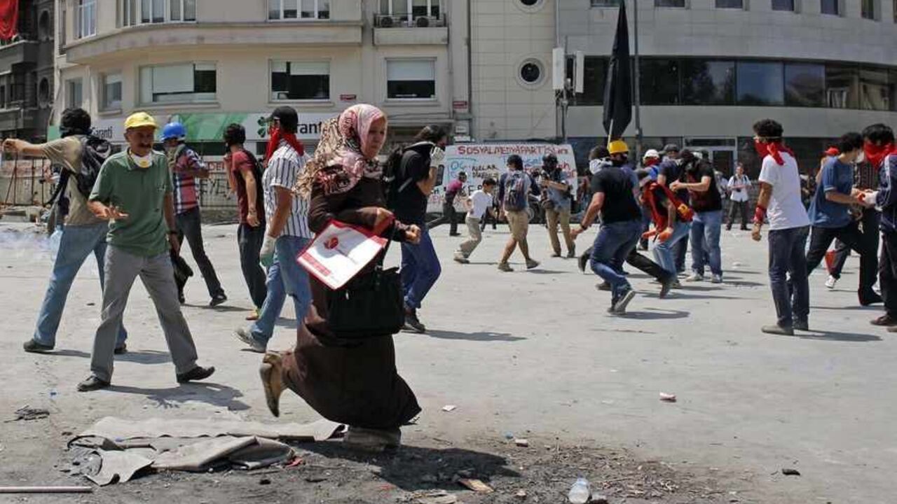 TURKEY-PROTESTS/ A woman runs as protesters taunt the riot police during a protest at Taksim Square in Istanbul June 11, 2013. Turkish riot police fired tear gas and water cannon at hundreds of protesters armed with rocks and fireworks on Tuesday as they tried to take back control of a central Istanbul square at the heart of fierce anti-government demonstrations. REUTERS/Murad Sezer (TURKEY - Tags: POLITICS CIVIL UNREST) - RTX10JWS