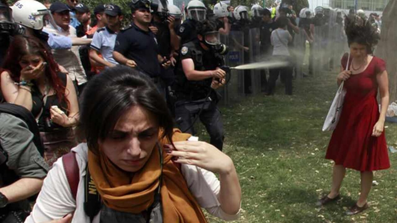 TURKEY/ A Turkish riot policeman uses tear gas as people protest against the destruction of trees in a park brought about by a pedestrian project, in Taksim Square in central Istanbul May 28, 2013. REUTERS/Osman Orsal (TURKEY - Tags: POLITICS CIVIL UNREST ENVIRONMENT TPX IMAGES OF THE DAY) - RTX103XA