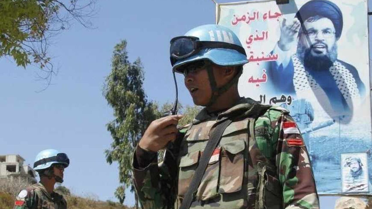An Indonesian soldier from the United Nations Interim Forces in Lebanon (UNIFIL) uses his walkie-talkie as he stands near a picture of Lebanon's Hezbollah leader Sayyed Hassan Nasrallah in the southern Lebanese village of Adaisseh July 24, 2013. Europe's decision to blacklist Hezbollah's "military wing" was triggered by the Lebanese movement's growing role in Syria, but the partial ban may have little practical impact due to fears of destabilising Lebanon and the wider Middle East.    REUTERS/Ali Hashisho (