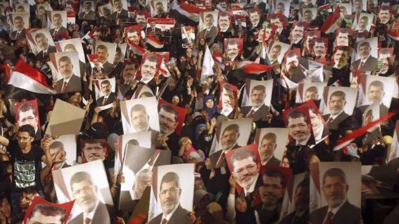 EGYPT-PROTESTS/ Members of the Muslim Brotherhood and supporters of Egypt's President Mohamed Mursi hold pictures of him as they react after the Egyptian army's statement was read out on state TV, at the Raba El-Adwyia mosque square in Cairo July 3, 2013. Egypt's armed forces overthrew elected Islamist President Mursi on Wednesday and announced a political transition with the support of a wide range of political, religious and youth leaders. A statement published in Mursi's name on his official Facebook page after head of